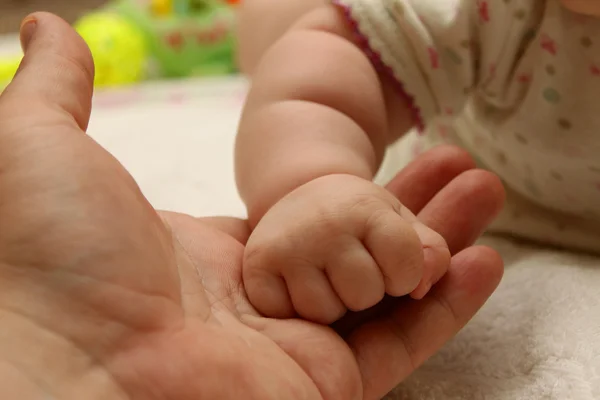 The hand of the child holds a hand of the adult close