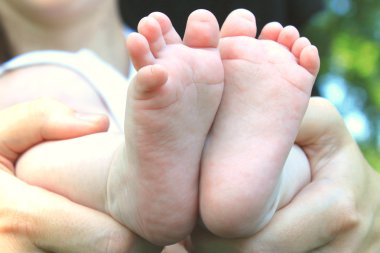 küçük ayakları Bebek annesi onun elinde tutar.