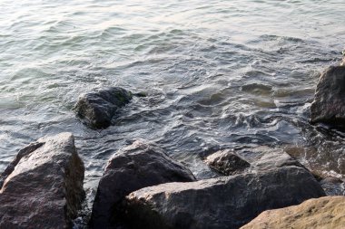 Siyah taşlar ve gri taşlar diğer büyük taşların ve deniz suyundaki küçük taşların arasında yakınlaşıyor.