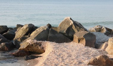 Siyah taşlar ve gri taşlar diğer büyük taşların ve deniz suyundaki küçük taşların arasında yakınlaşıyor.