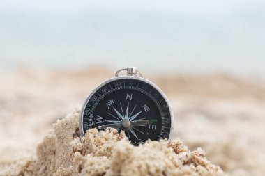 Pusula ile turizmin sembolü olarak plajda mavi denize karşı klasik navigasyon pusulası, pusula ile seyahat ve pusula ile açık hava aktiviteleri