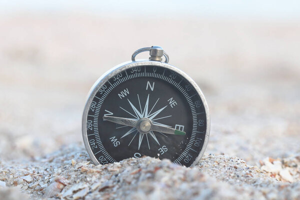Classic navigation compass on beach as symbol of tourism with compass, travel with compass and outdoor activities with compass