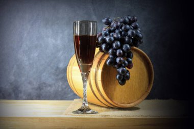 Kırmızı şarap fıçısının arka planında kırmızı şarap ve kırmızı şarap yapmak için bir demet üzümün yanında güzel, durgun bir hayat.