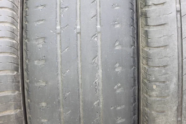 Old summer tire next to another old summer tire and worn tire next to smooth old tire close-up