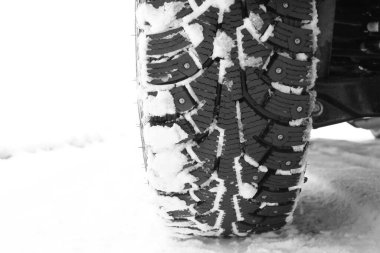 Winter studded tire on white snow as symbol of safe driving on winter tires in winter andneed to timely replace summer tires with winter tires