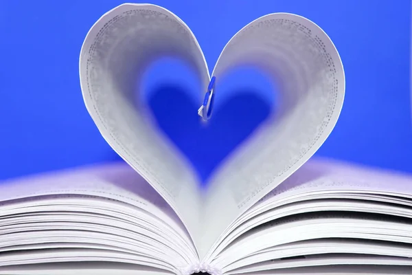 Open book in shape of heart on blue background