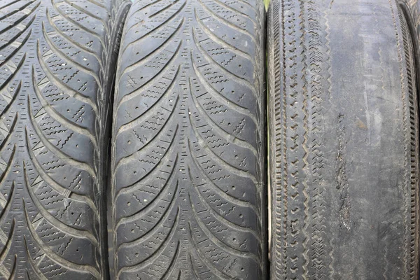 Old summer tire next to winter old tire as example of worn out summer tires and winter tires