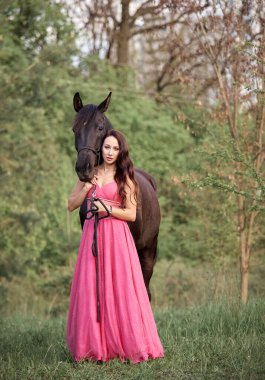Siyah bir atın yanında uzun saçlı, güzel bir kız.
