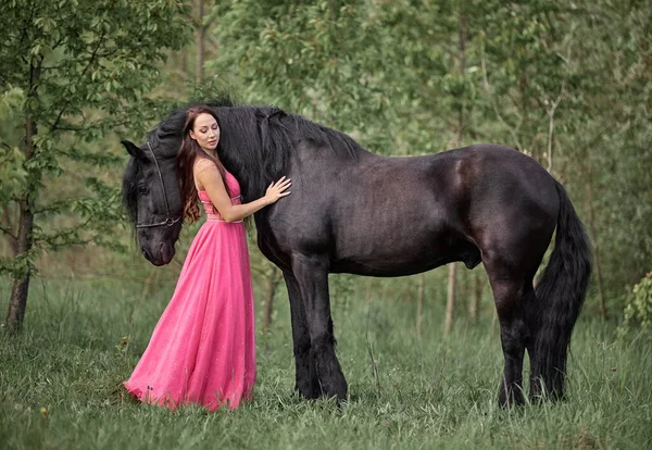 黒馬の横にあるドレスの美しい長髪の女の子 — ストック写真