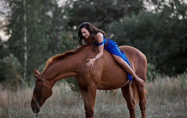 赤い馬に乗って青いドレスの美しい長髪の女の子 — ストック写真