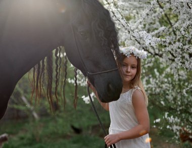 Bahçede bahar çelenginde beyaz saçlı güzel bir kız ve bir Frizya atı.