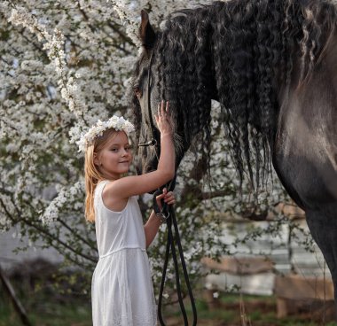 Bahçede bahar çelenginde beyaz saçlı güzel bir kız ve bir Frizya atı.