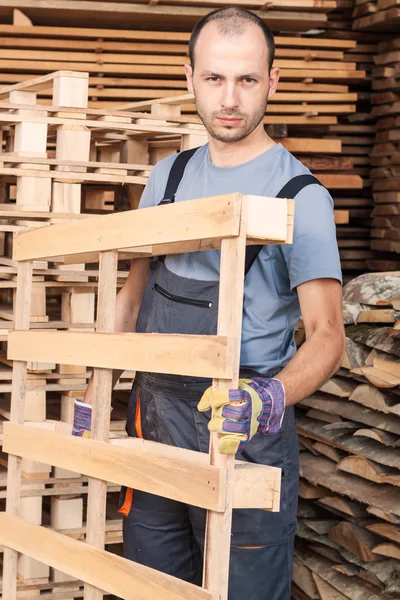 Warehouse worker moving wood pallets