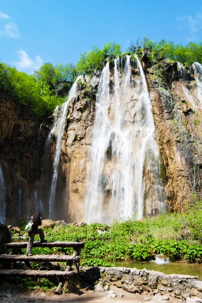 Young female tourist shooting a waterfal — Stock Photo, Image