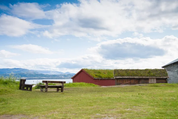 Houses with grass covered roofs and benches near a fjord — Stock Photo, Image