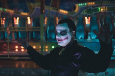 Man impersonating the Joker. Portrait of a man in a suit with clown makeup and green hair. Joker cosplay.