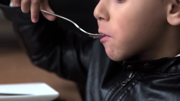 Der Junge im Café isst eine Torte mit Pudding — Stockvideo