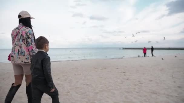 Mãe e filho estão andando ao longo da praia de outono juntos brincando — Vídeo de Stock