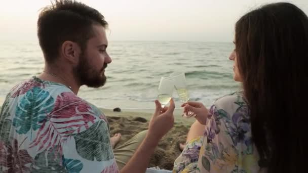 Дата в морі на світанку Любителі пікніка п'ють шампанське на пляжі — стокове відео