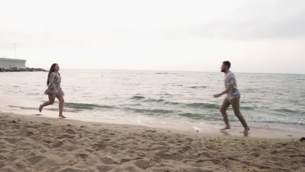 日の出のビーチでの日付恋人たちはビーチに沿って走ります — ストック動画