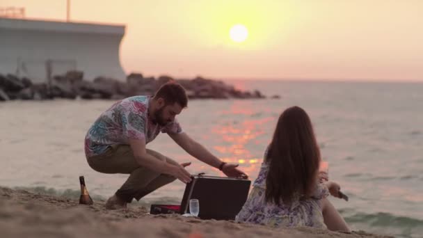 Fecha en el mar al amanecer Picnic Un hombre realiza una serenata para su amada — Vídeo de stock