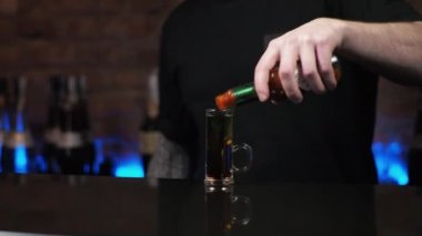 Barmen genç bir adam. Adam içkileri dolduruyor, alkollü içkiler hazırlıyor. Barda siyah mürekkep balığı var.