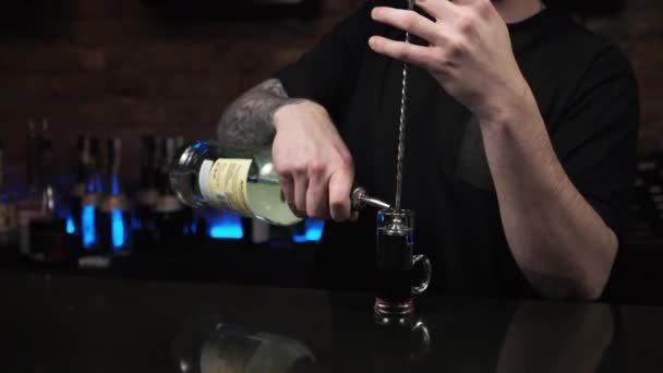 Бармен это молодой человек, парень наливает напитки, готовит выпивку черным каракатицам в баре. — стоковое видео
