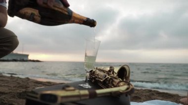 Şampanyayı güneşin arkaplanına karşı açan bir adam... Şafak söküyor yatağın üstüne. Piknik tarihi.