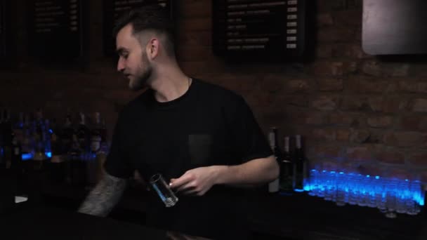 Barman é um homem jovem O cara serve bebidas, prepara tiros alcoólicos choco preto no bar — Vídeo de Stock