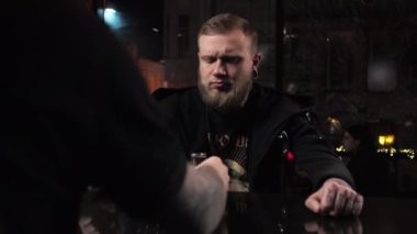 Barmen genç bir adam içki doldurur, barda alkol kokteyli hazırlar. Konuğa içki ikram eder.