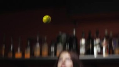 Geçiş hareketi. Kızıl saçlı kadın barmen margarita kokteyli hazırlıyor. Limon fırlatıyor.