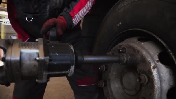 Un homme à l'aide d'un outil industriel détourne les boulons de roue d'un transport de marchandises — Video