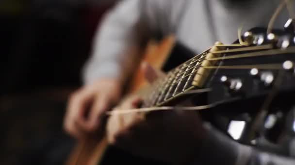 Een jongeman tunes een akoestische gitaar plukken van de snaren en muzikale noten — Stockvideo