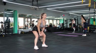 CrossFit. Sarışın bir kadın, kettlebell kaslarıyla antrenman yapıyor. Spor yapmak