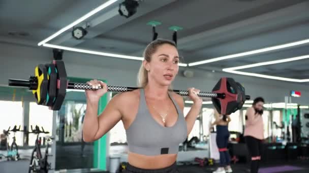 CrossFit Den blonda kvinnan tränar. Stretchar muskler Att idrotta. Knäböj med skivstång — Stockvideo