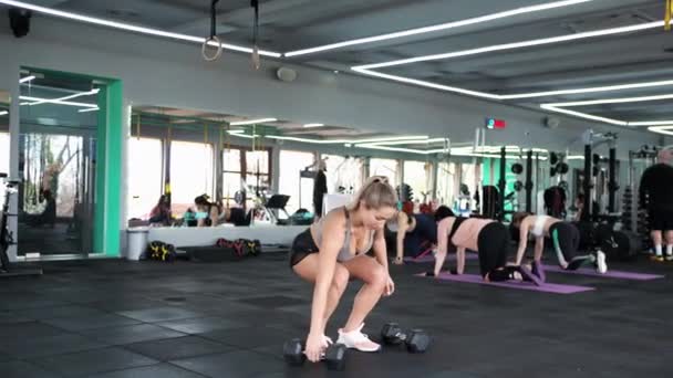 CrossFit Wanita pirang ini berolahraga otot Stretches Bermain olahraga mengangkat dumbbells — Stok Video
