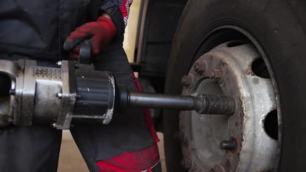 Человек с помощью промышленного инструмента крутит болты от грузового транспорта — стоковое видео