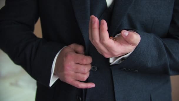 A young man put on a tuxedo indoors Shows a wedding ring in his hand — Stock Video