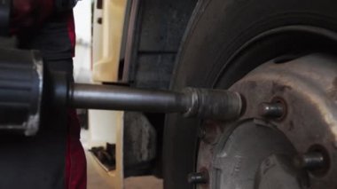 Endüstriyel bir aletin yardımıyla bir adam bir nakliye gemisinden tekerleği cıvatalar.