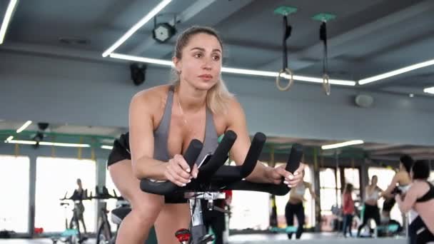 Korspassform Den Blonda Kvinnan Tränar Stretchar Musklerna Spelar Sport Cykeltrainer — Stockvideo