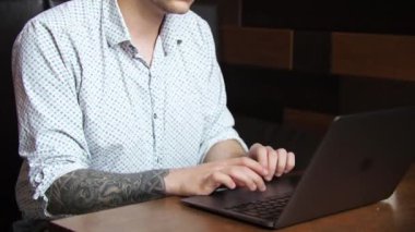 Serbest çalışan genç bir iş adamı esmer bir adam bir laptopun arkasında bir kafede oturuyor. Çalıştım, ders çalıştım, kahve içtim.