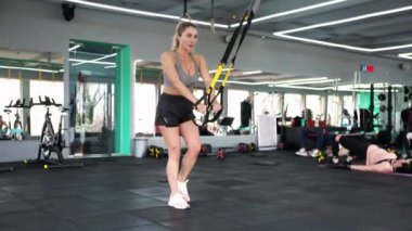 Çapraz Fit. Sarışın kadın egzersiz yapıyor. Kaslarını gerer. Spor yapıyorum. TRX ile esnetiliyor