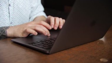 Serbest çalışan genç bir iş adamı esmer bir adam bir laptopun arkasında bir kafede oturuyor. Çalıştım, ders çalıştım, kahve içtim. Yakın plan..