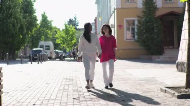 Beyaz kızıyla birlikte Afro-Amerikalı genç bir anne şehir parkında geziyor.