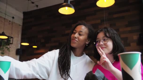 Молодая Афроамериканская Мать Белой Дочерью Сидит Кафе Разговаривает Пей Какао — стоковое видео