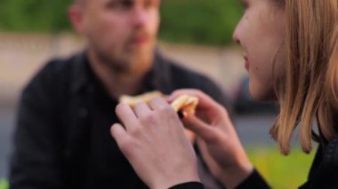 Randevu. Genç adam ve kadın şehir parkında, otoparkta, çimlerde, çimlerde. Pizza yiyorlar. Oynaşmak, eğlenmek, gülümsemek. Kahve iç..