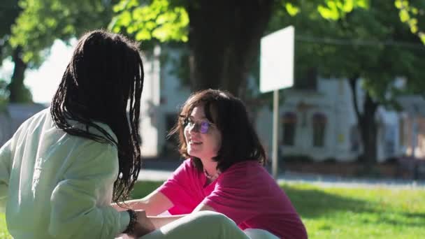 Madre Joven Afroamericana Con Hija Blanca Sentada Parque Césped Hablando — Vídeos de Stock