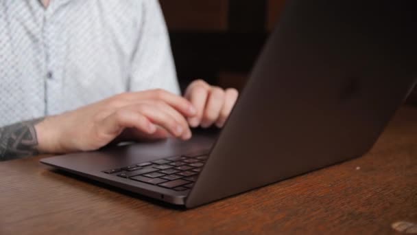 若いフリーランスのビジネスマンのブルネットがノートパソコンの後ろのカフェに座っています 仕事や勉強 コーヒーを飲む — ストック動画