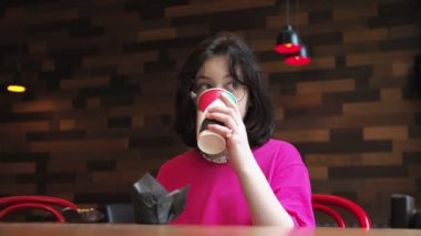 Beyaz kızıyla birlikte Afro-Amerikalı genç bir anne bir kafede oturuyor ve konuşuyor. Kakao iç. Tatlı ye..