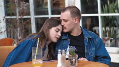 Genç bir çift. Denim giysileri. Eski bir restoranda randevuda, dışarıda. Konuşuyorlar. Harikaydı. Sarılmak..